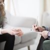 Cropped photo of a therapist writing down notes during therapy with her female patient